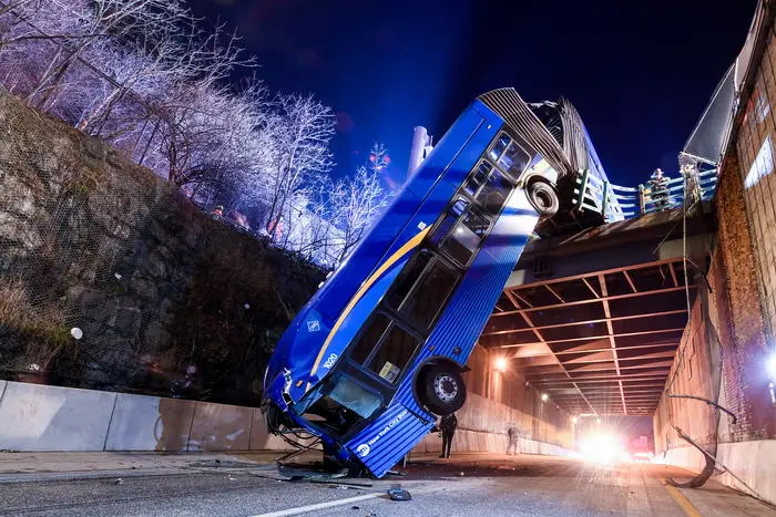 Photographs show a tandem 'accordion' bus dangling off the side of an overpass, with the front of the bus crashed on the ground
